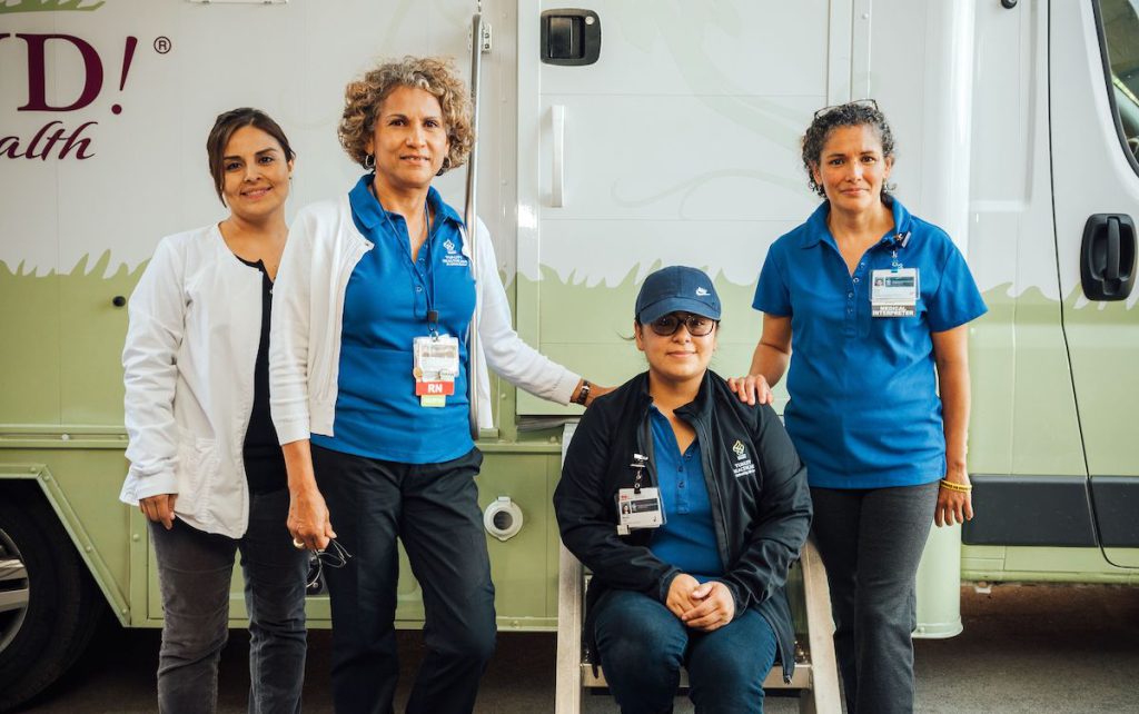 A group of Salud workers in mixed seated and standing pose facing the camera