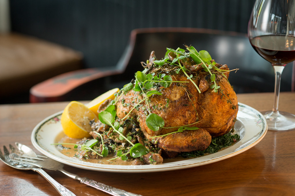 A plate full of food with silverware on the left side and a glass of wine on the right side